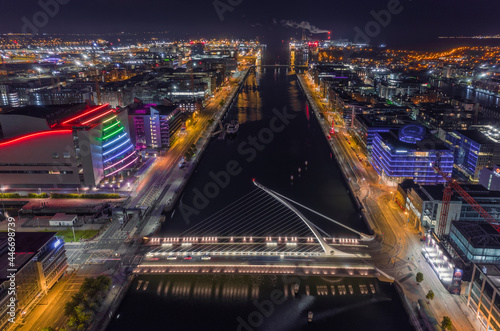 Aerial view of Samuel Beckett Bridge crossing the Liffey River at night with city skyline in background, Dublin, Ireland. photo