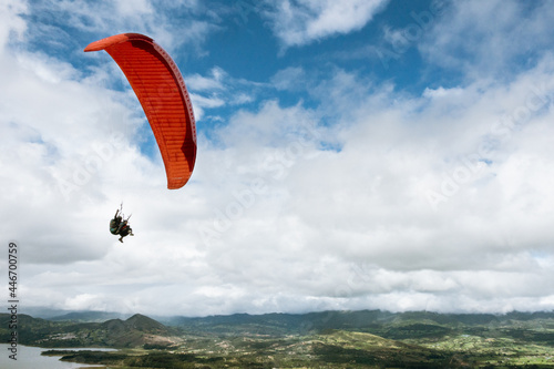 Paraglider tandem fly with blue sky,tandem paragliding over the mountains in a cloudy day
