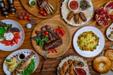 chateaubriand steak with grilled vegetables, rack of lamb, lula kebab of veal, uzbek pilaf, salad with buratta cheese, chicken tabacco, pomegranate,  fried sea bass on wooden table top view food