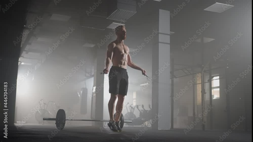 Young man exercising using skipping rope in gym. Athletic man training hard at the gym. Young man exercising using skipping rope in gym. Athletic man training hard at the gym.