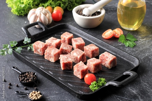 Raw Frozen Saikoro Wagyu Cubes or Dice Beef Steak on Black Steak Plate with Spice and Vegetable
