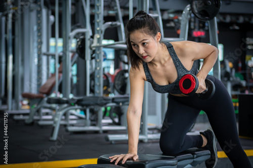 Sport woman doing exercises with dumbbell at gym ,she exercise for good healthy , bodybuilding and muscle.
