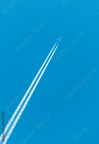 JET CROSSING A BLUE SKY IN DIAGONAL WAY LEAVING WHITE TRAILS 