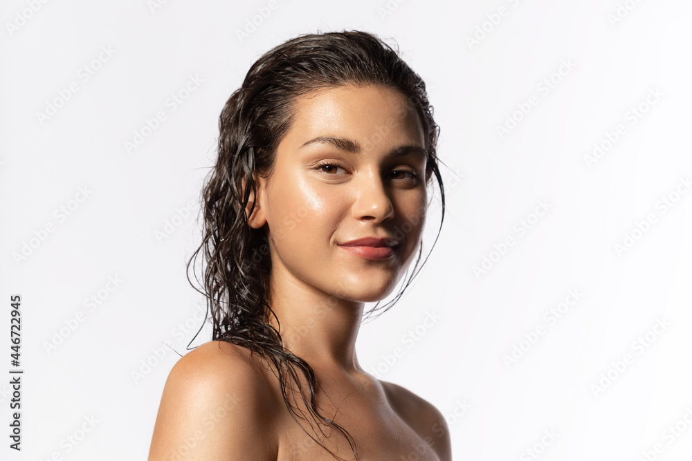 Beautiful young woman with clean perfect glowing skin, wet hairs. Portrait of smiling girl with bare shoulders on gray studio background. Skincare and wellness. Natural woman beauty. - obrazy, fototapety, plakaty 