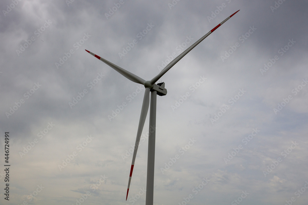 Industrial wind turbines are on the plain. Huge windmills stand on the plain under a gloomy sky. Industrial wind turbines are on the plain. Huge windmills stand on the plain under a gloomy sky.