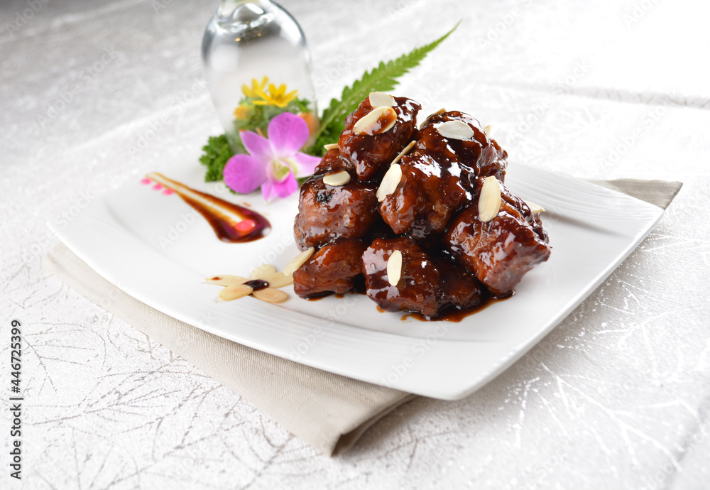 Stir fried dark plum sweet and coffee sauce pork spare ribs meat with almond in white background asian banquet menu Stir fried dark plum sweet and coffee sauce pork spare ribs meat with almond in white background asian banquet menu