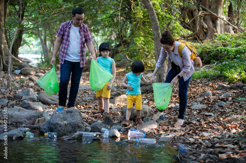 Asian Family volunteer picking up a plastic bottle on river