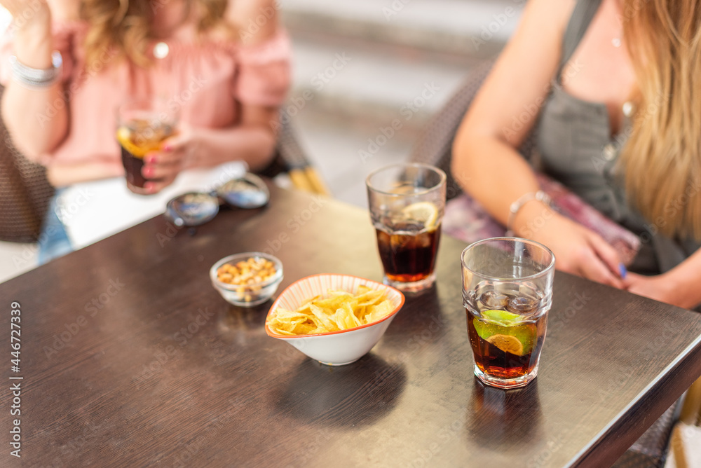 Cropped view of some drinks and snacks being consumed by adult friends