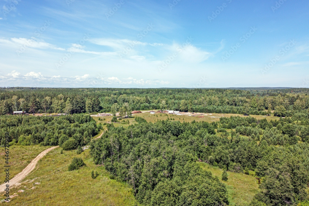 Top view of industrial facilities in the forest against a blue sky with white clouds