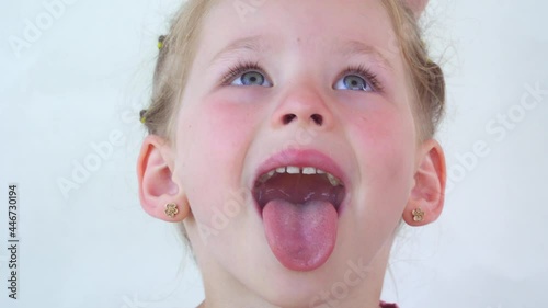 little girl show tongue, throat. portrait with wide open mouth and protruding tongue. with clear view pulls out long tongue. soft palate and mouth to dentist. mouth is wide open, tongue is stuck out.