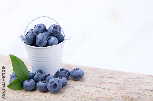 
Blueberries in a bucket on a wooden table.