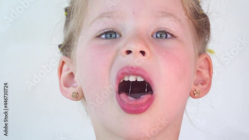 saliva. Close up girl collects drool on her tongue. The child shows the throat and palate to the doctor. Health concept. Play and stick out your tongue and teeth. Salivation in children.