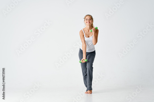 sportive woman with dumbbells in hands workout gym light background