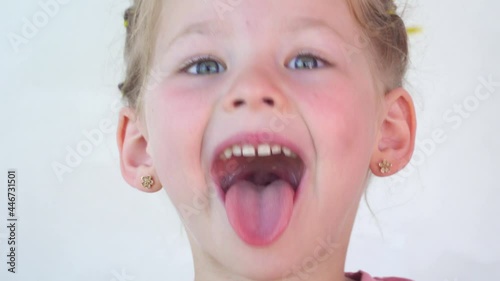 little girl show tongue, throat. portrait with wide open mouth and protruding tongue. with clear view pulls out long tongue. soft palate and mouth to dentist. mouth is wide open, tongue is stuck out.