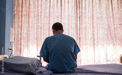 Patient in patient set is sitting on the bed in the private room in the hospital. Isolated patient in hospital. Isolation covid ward.