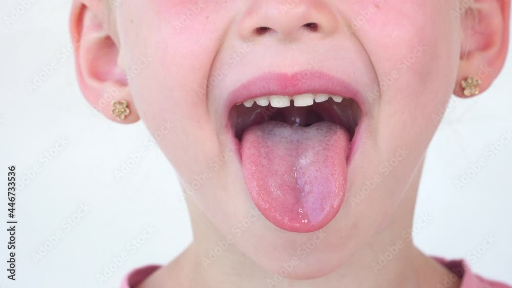 Little girl plays with tongue and saliva. Close-up of a girl face ...    