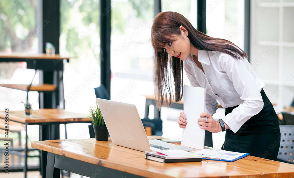 Young attractive asian busineswoman prepare documents to finish work while standing at office desk. Young attractive asian busineswoman prepare documents to finish work while standing at office desk.