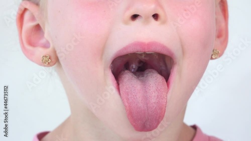 little girl show tongue, throat. child do gymnastics. kid Training of muscles speech therapy. Happy baby on white background. Place for text. portrait with wide open mouth and protruding tongue.