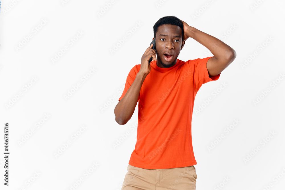 perplexed man of African appearance talking on the phone on a light background perplexed man of African appearance talking on the phone on a light background