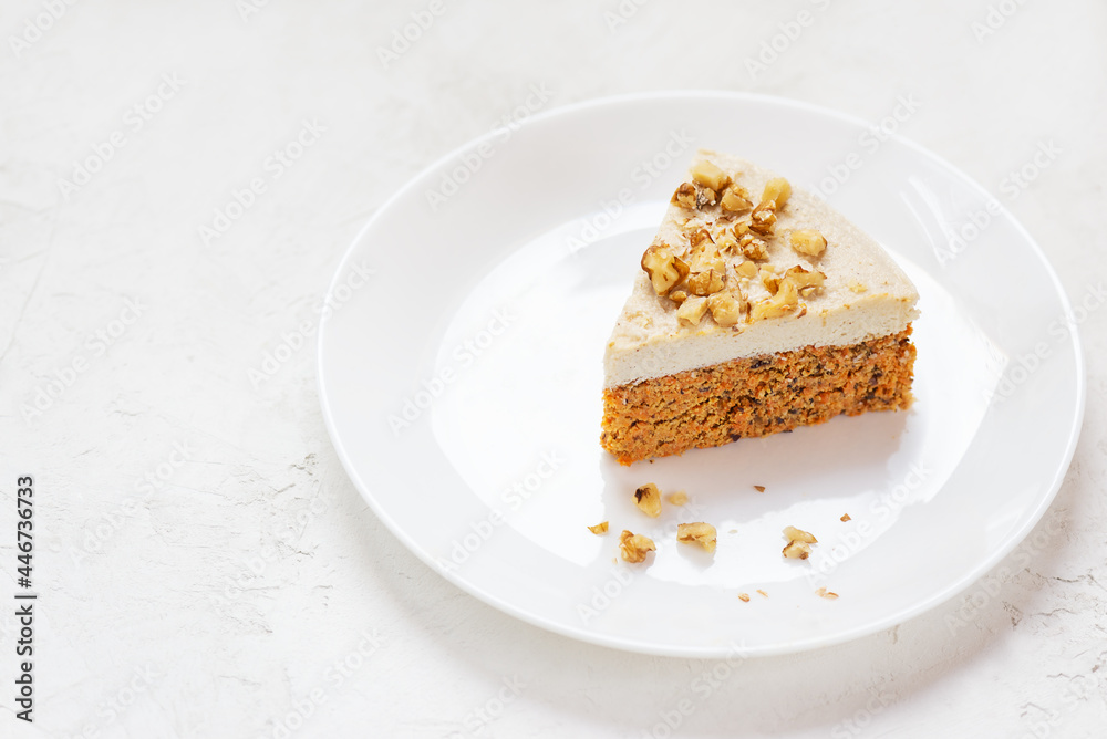 Slice of carrot cake with coconut cream and walnuts on a white plate. Raw dessert, no baked goods. Sugar, gluten and lactose free. Slice of carrot cake with coconut cream and walnuts on a white plate. Raw dessert, no baked goods. Sugar, gluten and lactose free.