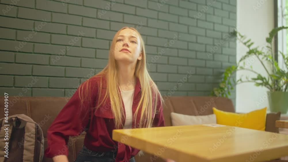 Female student sitting down at coffee shop table, ready to order, coffee break Female student sitting down at coffee shop table, ready to order, coffee break