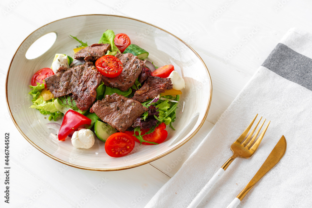 Fillet of beef with vegetable salad on wooden table Fillet of beef with vegetable salad on wooden table