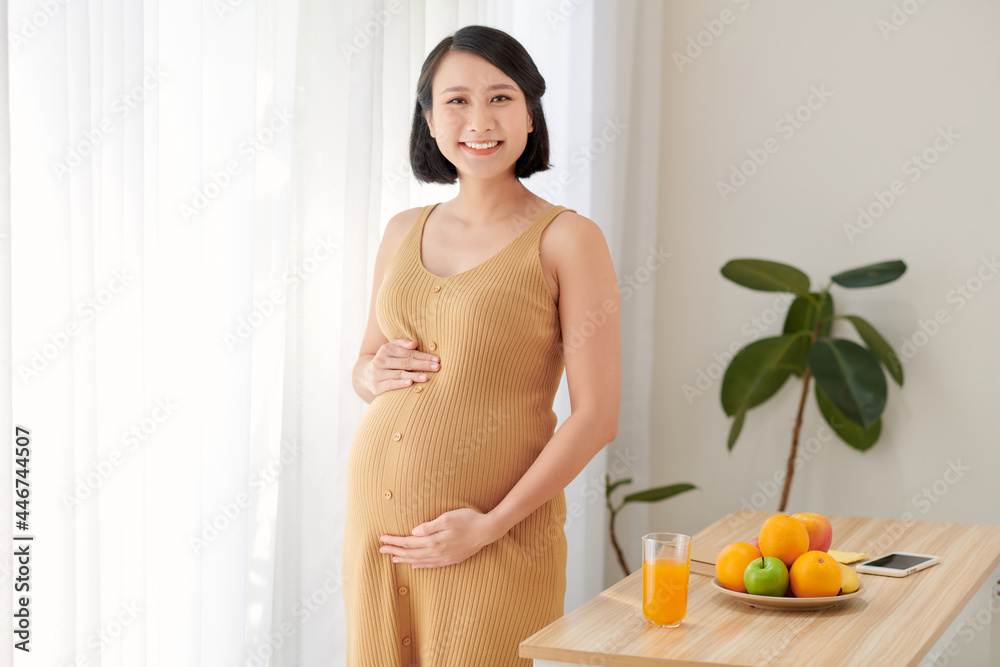 Beautiful pregnant woman standing near table with fresh vegetables Beautiful pregnant woman standing near table with fresh vegetables