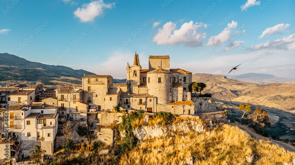 Aerial view of medieval stone village,the highest village in Madonie mountain range,Sicily,Italy.Church of Santa Maria di Loreto at sunset.Picturesque stone houses,narrow cobbled streets,views of town
