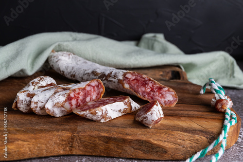 Italian sausage snack. Delicious dry sausage, close-up on a wooden board.