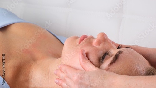 Facial massage beauty treatment. Close up of a young womans face lying on back, getting face lifting massage, pinch and roll technique