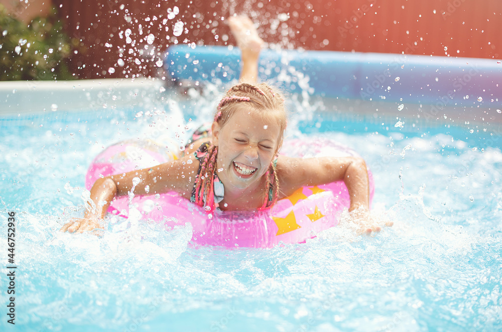 Funny little girl swims in a pool in an pink life preserver