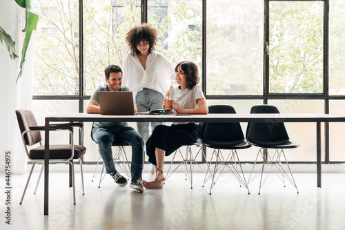 Group of young coworkers looking at laptop in spacious bright loft coworking space. Creative ideas. Startup. Teamwork. photo