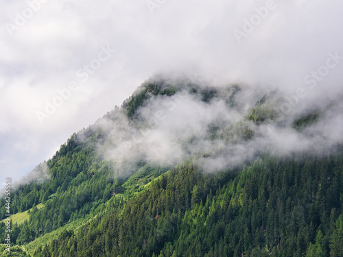 wooded mountain slope in swiss alps with fog and clouds in the morning. Seen in the Swiss Alpine valley "val d'Anniviers" (in German Eifschtal) in the canton of Valais