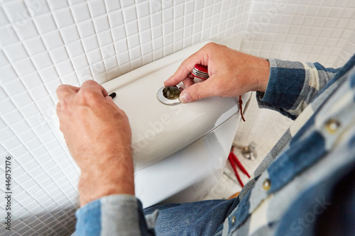 Hands install spare parts in the defective toilet cistern