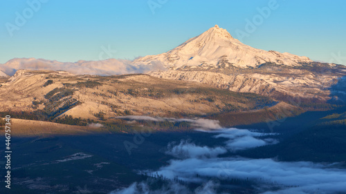 Mountain ridge with Mt Jefferson covered by fresh snow and fog in the valley in the morning at sunrise.