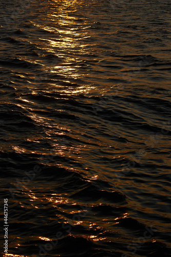 夕焼けの海面の光の反射と波の風景