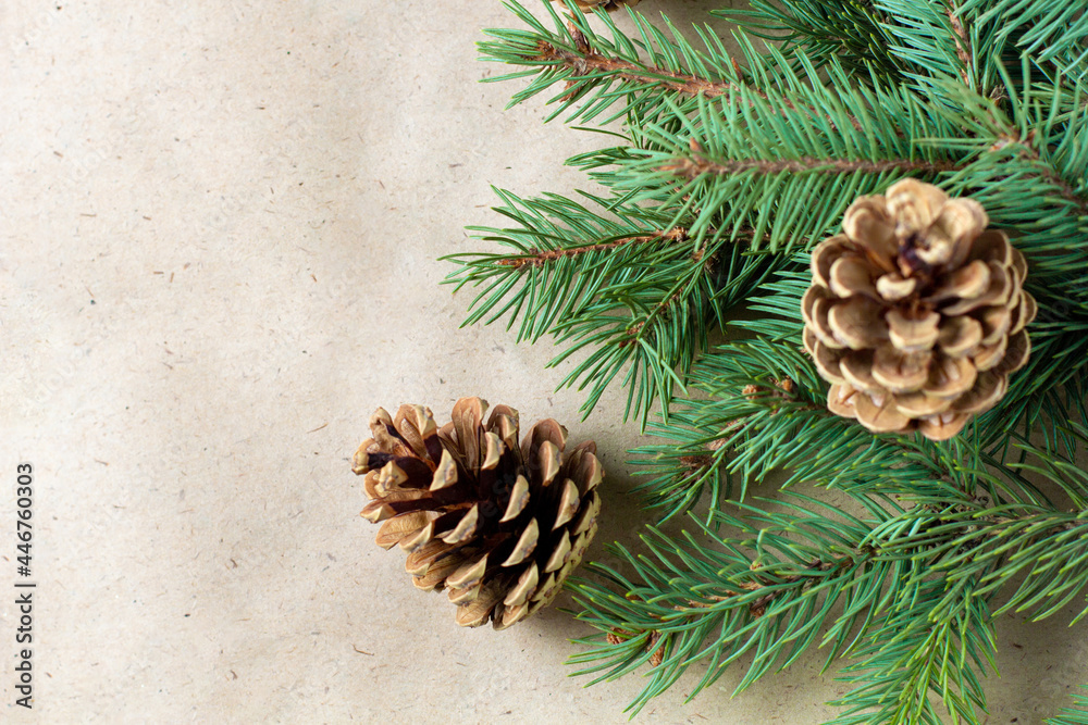 Corner of fir tree branch with cones on craft paper for christmas card with copy space for text. Top view, flat lay Corner of fir tree branch with cones on craft paper for christmas card with copy space for text. Top view, flat lay