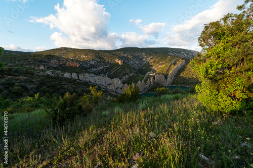 imagen de paisaje de una cordillera de piedra entre los árboles y un embalse de agua 