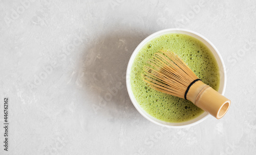 Matcha tea and a bamboo whisk on a gray concrete background. Cooking matcha green tea. Japanese traditional drink. View from above. Space for text.