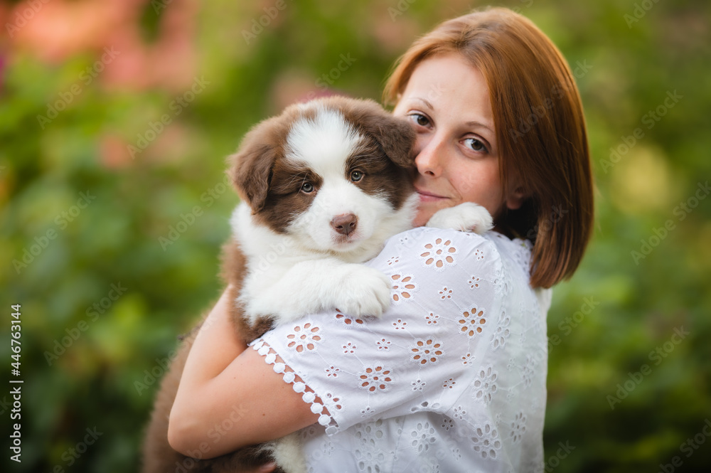 Young white female carrying a lovely border collie puppy in a park Young white female carrying a lovely border collie puppy in a park