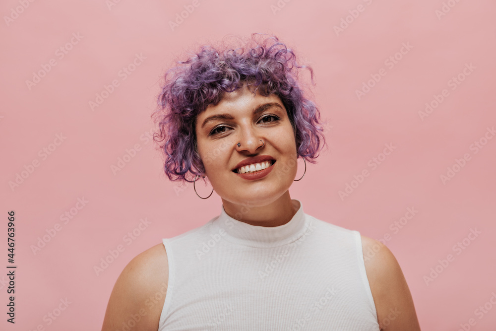 Beautiful curly woman with lilac hair with snow-white smile looks at camera. Cute unusual girl posing on isolated background.. Beautiful curly woman with lilac hair with snow-white smile looks at camera. Cute unusual girl posing on isolated background..