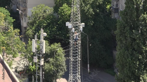 Mountaineering construction worker descends from 5G tower structure on roof of building. Speed up video from top to basement of tower mast structure. Industrial mountaineering works on rooftop