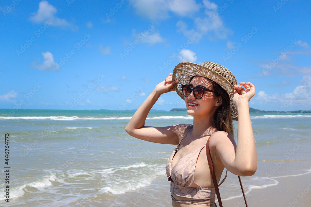Portrait of beautiful Asian woman with big hat and sunglasses enjoy spending time on tropical sand beach blue sea, happy smiling female resting and relaxing on summer holiday vacation. Portrait of beautiful Asian woman with big hat and sunglasses enjoy spending time on tropical sand beach blue sea, happy smiling female resting and relaxing on summer holiday vacation.