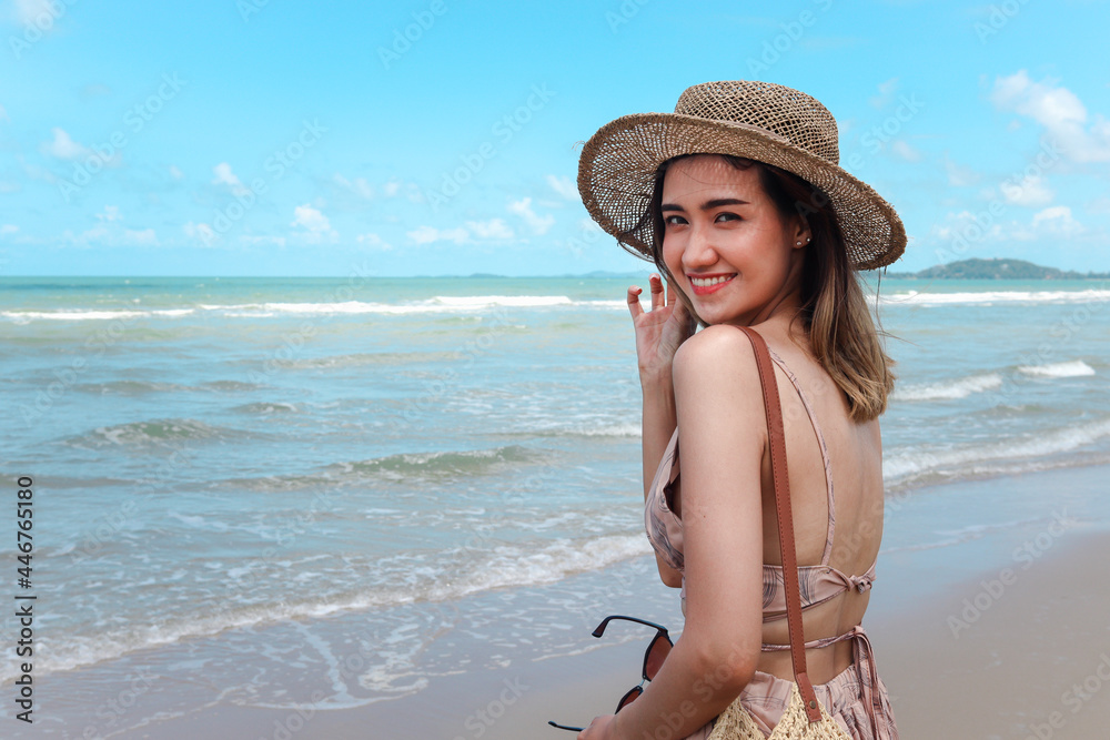 Portrait of beautiful Asian woman with big hat and sunglasses enjoy spending time on tropical sand beach blue sea, happy smiling female resting and relaxing on summer holiday vacation.