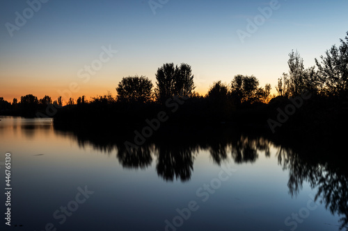 reflection of the horizon with the trees on the lake with the last lights of the day