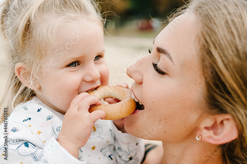 Mom with daughter eat cookies on the beach. Girl and mother have picnic on the seaside.