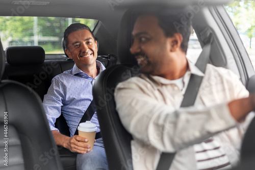 transportation, vehicle and people concept - happy smiling middle aged male passenger with coffee cup talking to taxi car driver