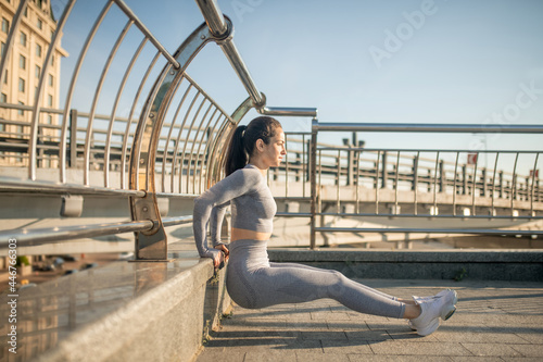 Fit girl in grey sportswear doing push ups and looking concentrated © zinkevych