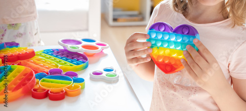 Little girl,kid,child plays with colorful pop it children's room, bedroom.Funny trendy silicone antistress colorful sensory push toy popit.Flapping fidget.Rainbow color.Cure of autism.Stress reliever