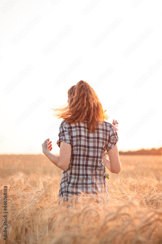 Girl with flowersin hands in a wheat field at sunset Girl with flowersin hands in a wheat field at sunset